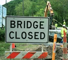 Sign in front of construction site reading "Bridge Closed"