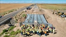 A collection of workers standing in front of a newly completed bridge segment.